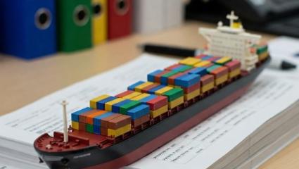 modellino di nave da carico sopra dei registri su un tavolo di ufficio, sullo sfondo altri faldoni